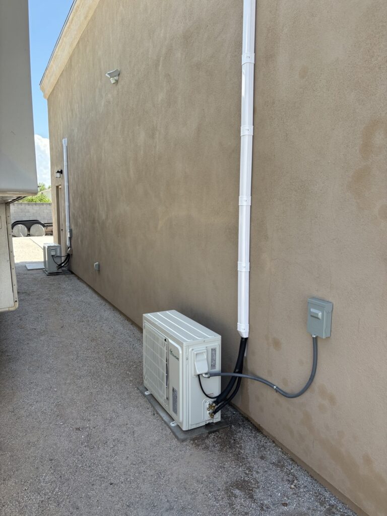 Mini split condenser wiring beside a home